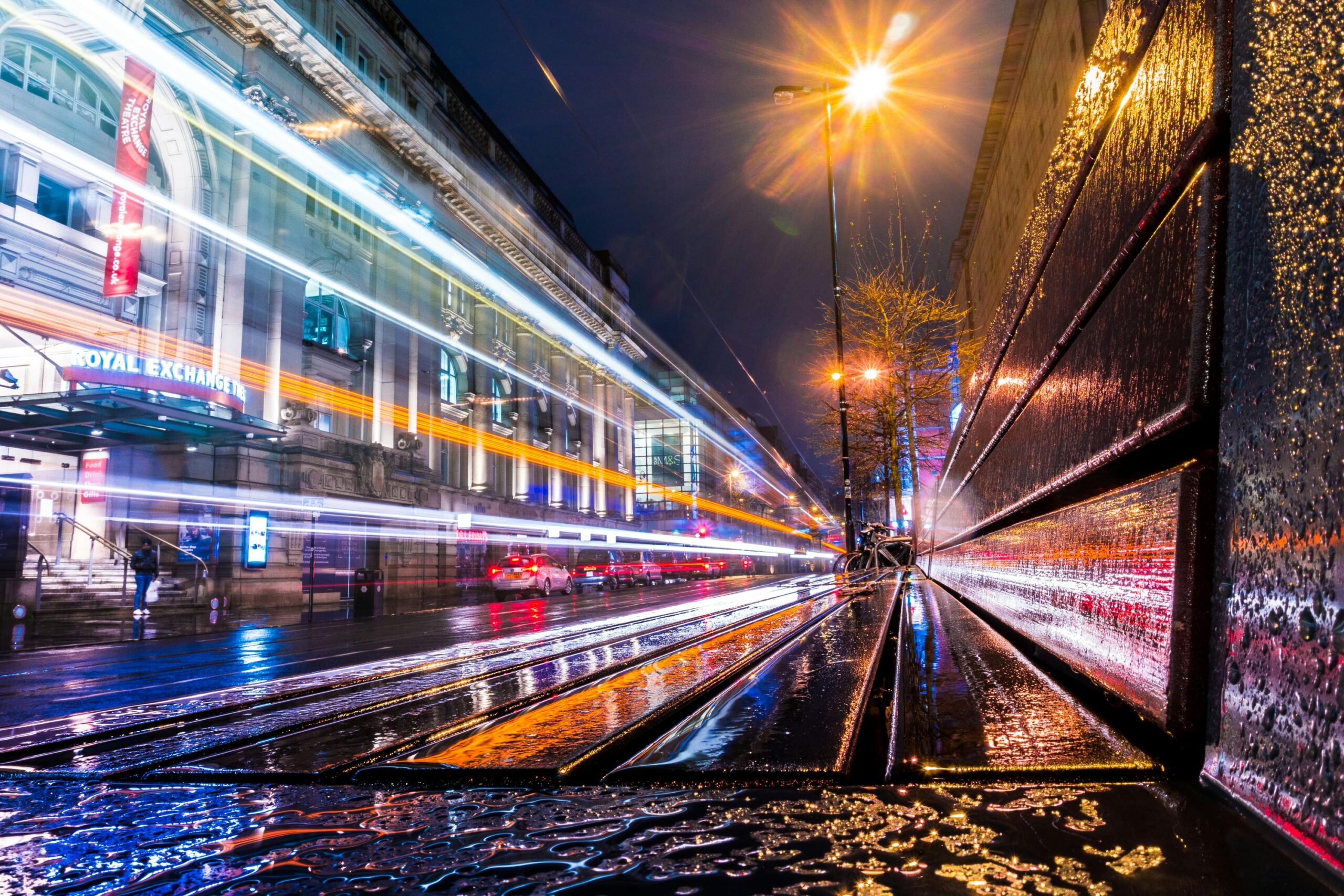 Vibrant long exposure photo of city lights and wet streets in Manchester, UK.