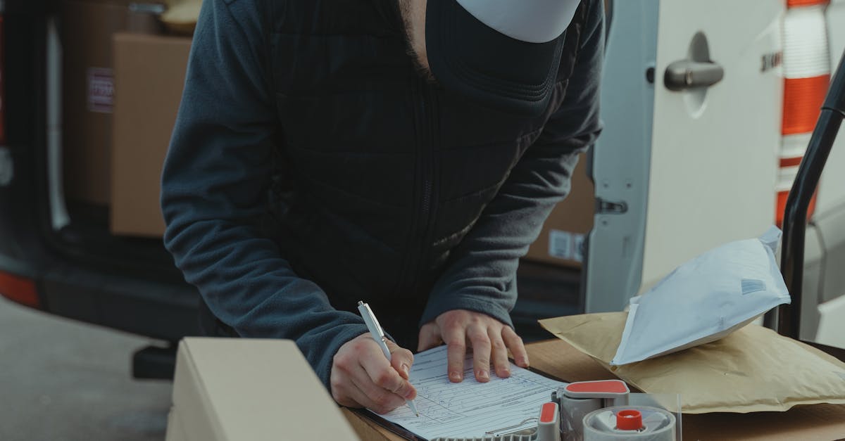Courier organizing packages from a van, preparing for delivery in a logistics setting.