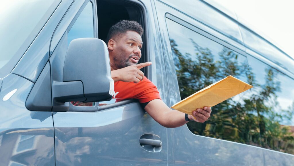 Courier in a van delivering a package through the window on a sunny day.